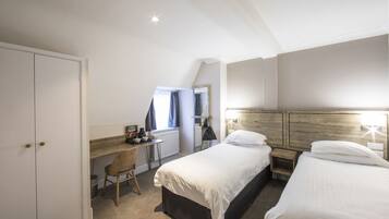 A hotel room with a bed, a desk, a chair, and a wardrobe.