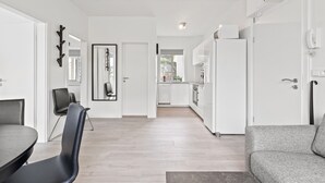A modern, minimalist living room with a dining area, a grey sofa, and a black chair. - Odinn Reykjavik Odinsgata Apartments (Reykjavik)