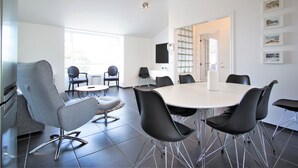 A modern meeting room with a round table, black chairs, and a grey armchair. - Odinn Reykjavik Odinsgata Apartments (Reykjavik)