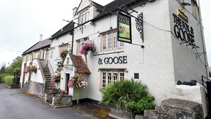 A traditional white building with a sign reading "The Fox & Goose." It features a staircase leading to the entrance, flower boxes, and a small garden area. - Fox & Goose, Barrow Gurney by Marston's Inns (Bristol)