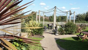 A garden patio with a gravel path leading to a seating area with tables and chairs. - Fox & Goose, Barrow Gurney by Marston's Inns (Bristol)