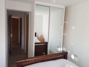 A hotel room with a wooden bed, a bedside table with a lamp, and a large mirror reflecting the room. - Oxford Modern Guest House (Oxford)