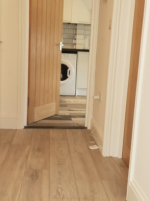 A hallway leading to a laundry area with a washing machine and cabinets. - Oxford Modern Guest House (Oxford)