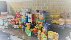 Una encimera de cocina con distintos alimentos y cajas, como cereales, leche y frutas.