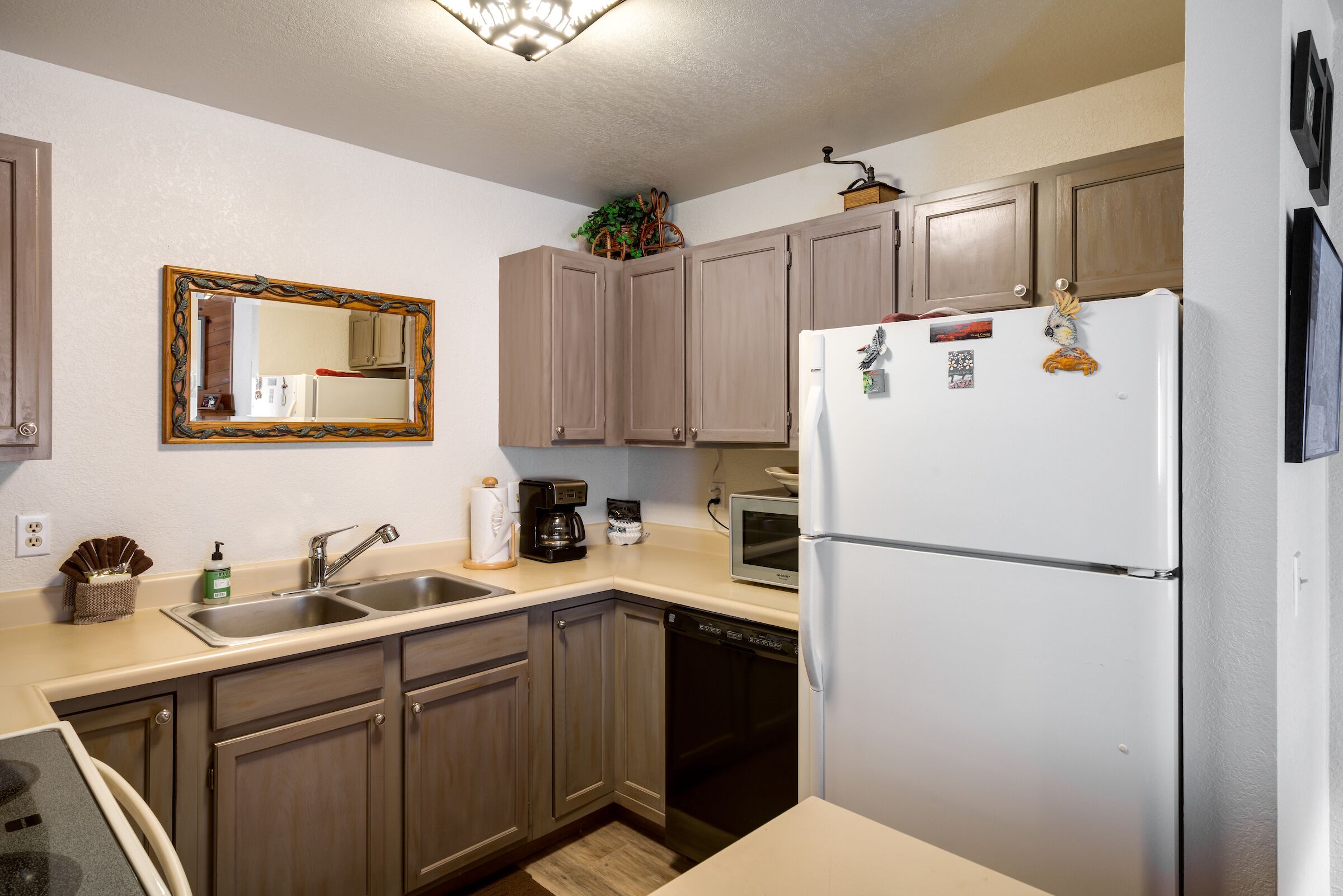 A kitchen with wooden cabinets, a white refrigerator, a microwave, and a dishwasher.