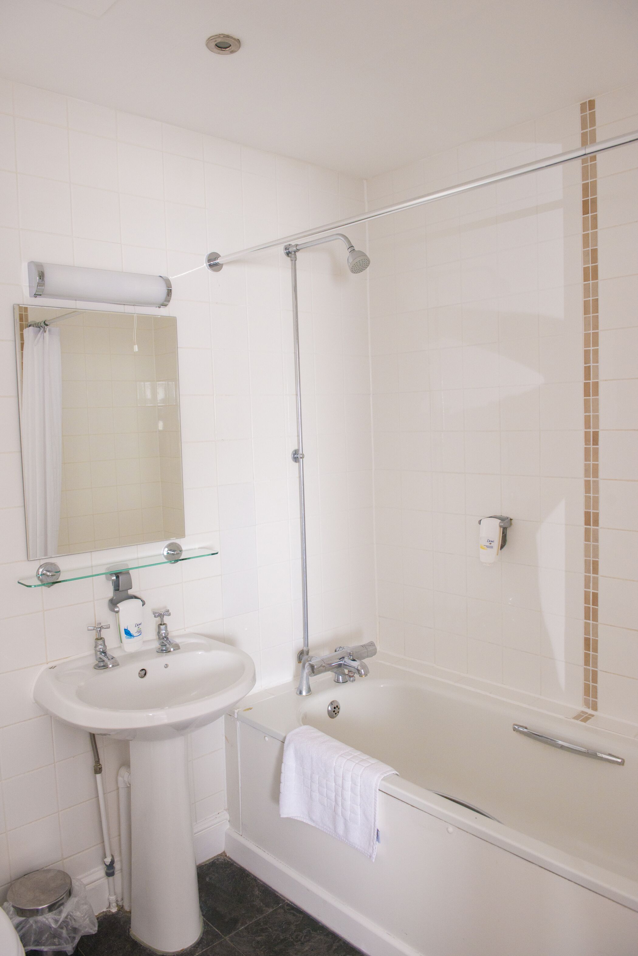 Un baño con lavamanos, espejo y bañera blancos.