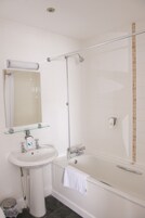 Un baño con lavamanos, espejo y bañera blancos.