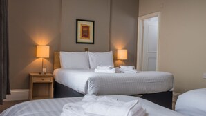 Ein Hotelzimmer mit zwei Betten, einem gerahmten Bild an der Wand und zwei Nachttischlampen.