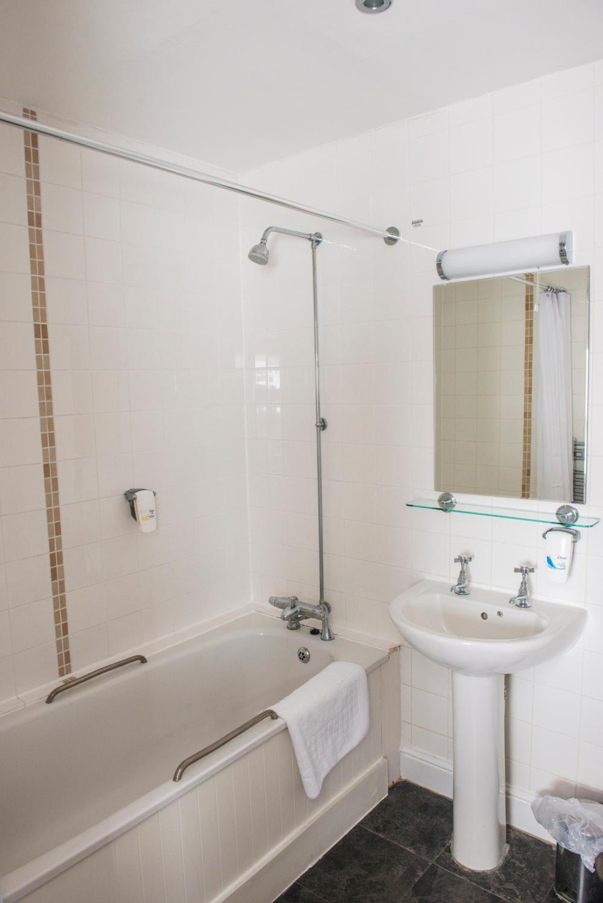 Un baño con bañera, ducha envuelta en vidrio, lavabo y espejo.