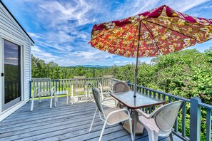 Enjoy a serene outdoor space with a covered seating area, lush greenery, and a mountain view.