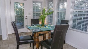 Un coin repas avec une table en verre, quatre chaises et une plante en pot.