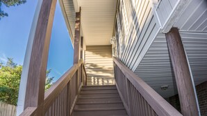 Un escalier en bois mène à un espace abrité d’où l’on peut admirer le ciel et les arbres.
