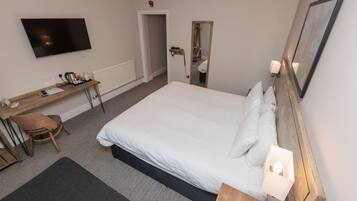 Une chambre d’hôtel équipée d’un lit, d’un bureau, d’une chaise, d’une télévision et d’un miroir.