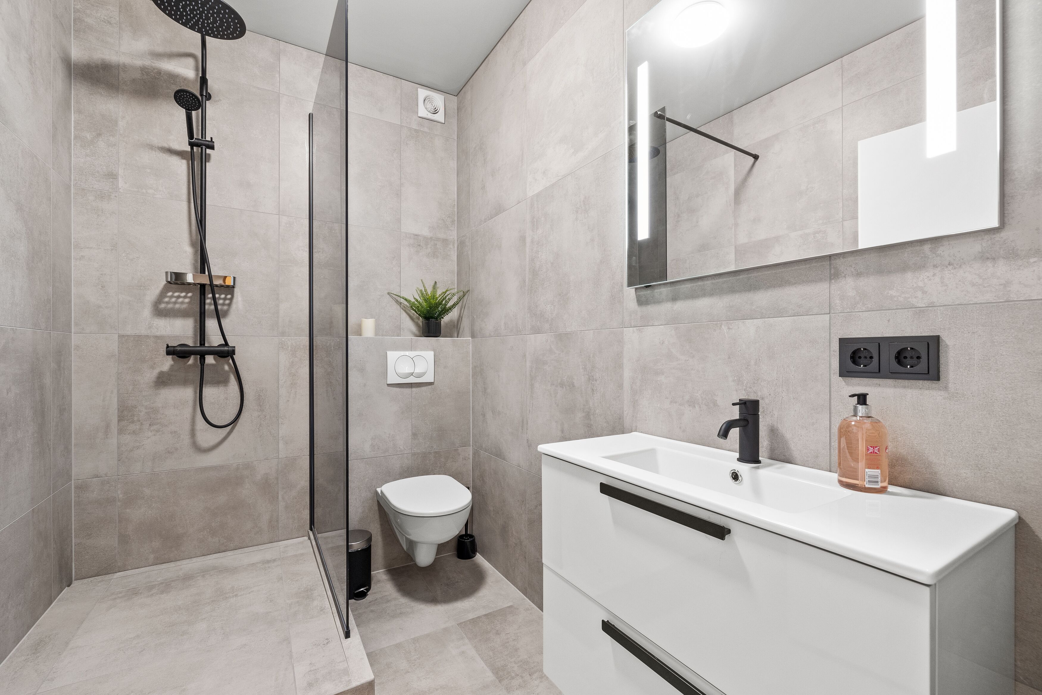 Un baño moderno con ducha, inodoro y lavamanos.