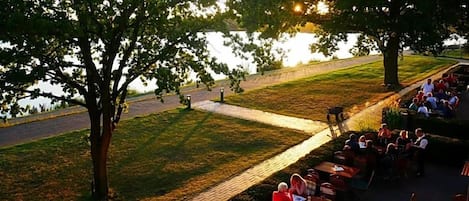 An outdoor seating area with tables and chairs, a pathway, and trees.