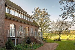 En toetages murbygning med balkon og trappe op til øvre etage.