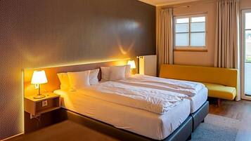 Ein Hotelzimmer mit einem großen Bett, Nachttischen, einer Bank und einem Fenster mit Vorhängen.
