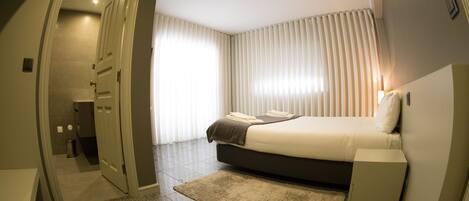 A bedroom with a bed, bedside table, and a small cabinet.