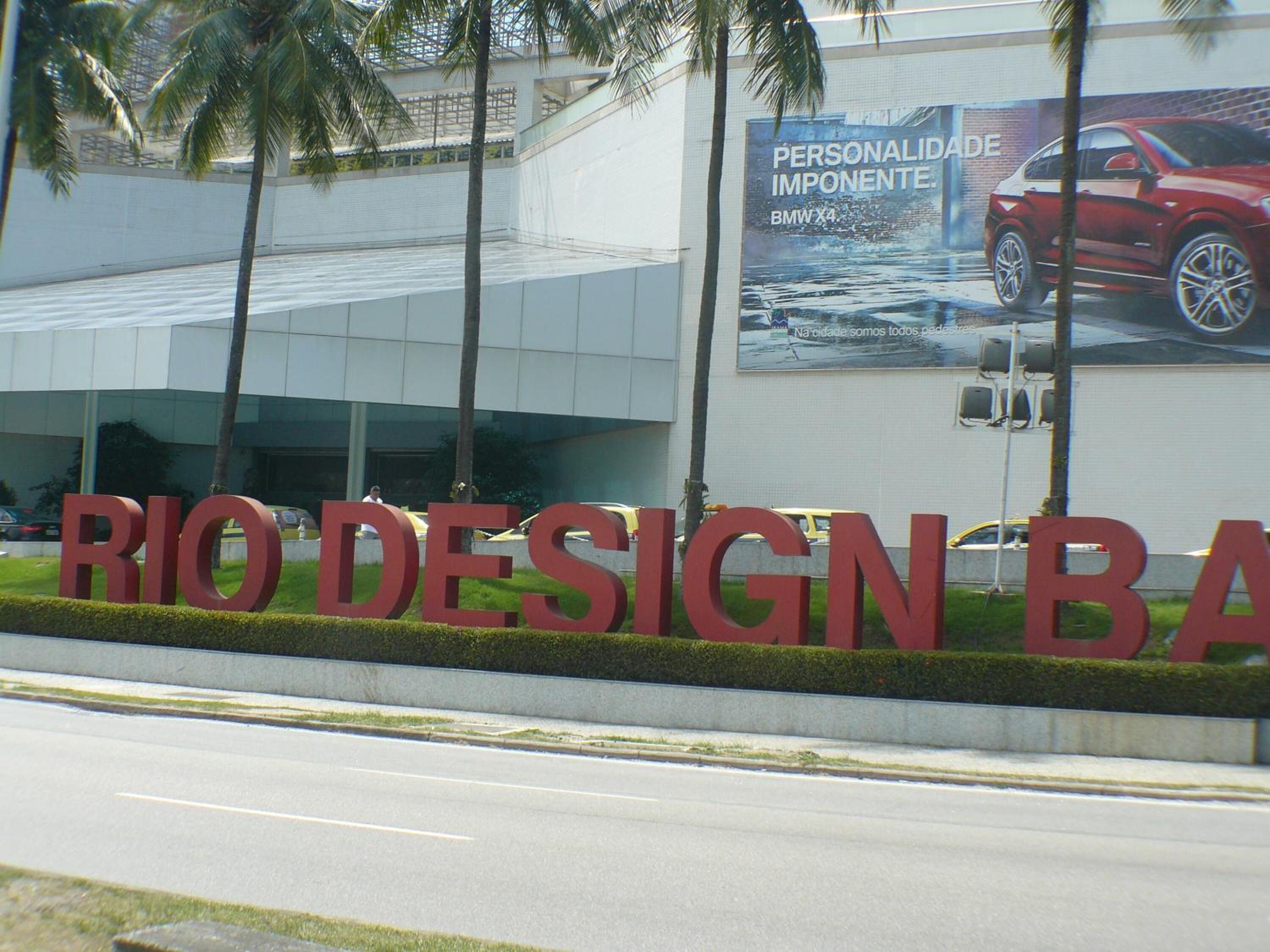 A large sign for Rio Design Bar with a BMW advertisement on the building behind it.