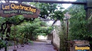 Ein Weg, der zu einem Empfangsbereich führt, mit einem Schild, auf dem 'Los Quebrachos Hospedaje Y Camping' steht.