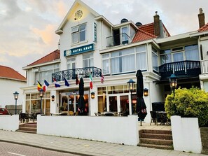 Hotel com varanda, área de estar ao ar livre e bandeiras.