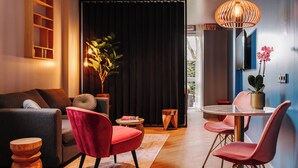 Una sala de estar moderna con un sofá, sillas rojas, una mesa de comedor y una planta en maceta.