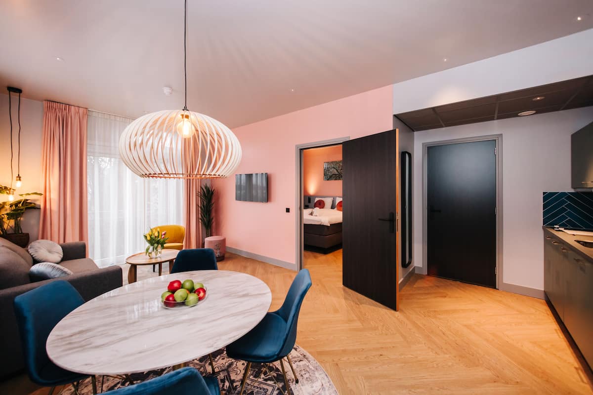 Ein modernes Wohnzimmer mit einem runden Marmortisch, blauen Stühlen, einer Pendelleuchte und einem Sofa.