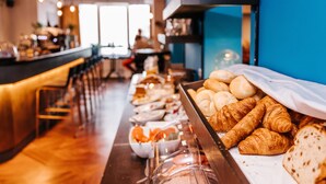 Un bufé con diversos alimentos, entre ellos pasteles y frutas, en un moderno restaurante.