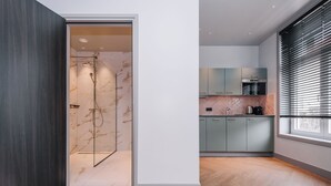 Una cocina moderna con armarios de colores claros, horno empotrado y ventana con persianas.