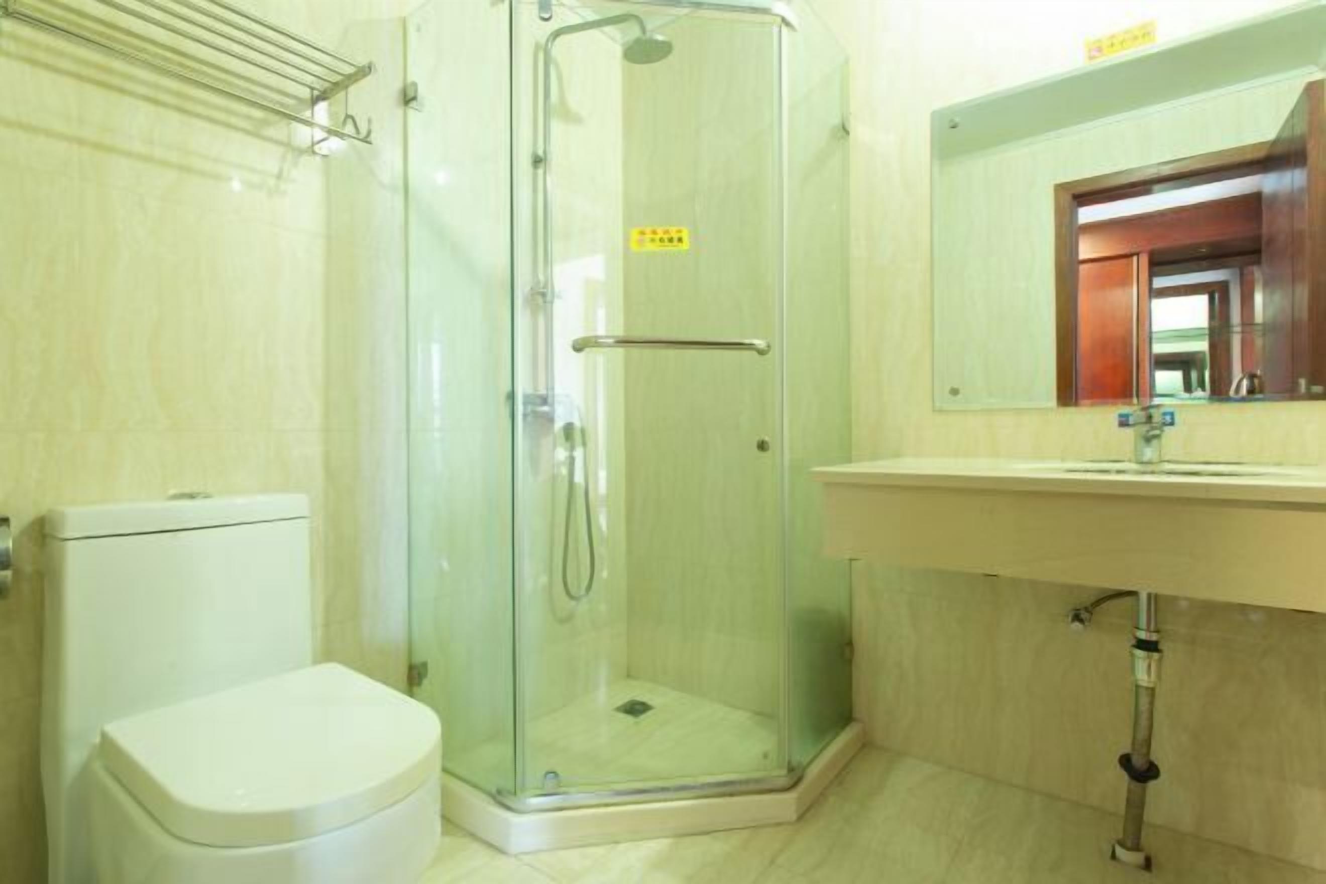 Un baño con ducha envuelta en vidrio, un inodoro blanco y un lavamanos con espejo.