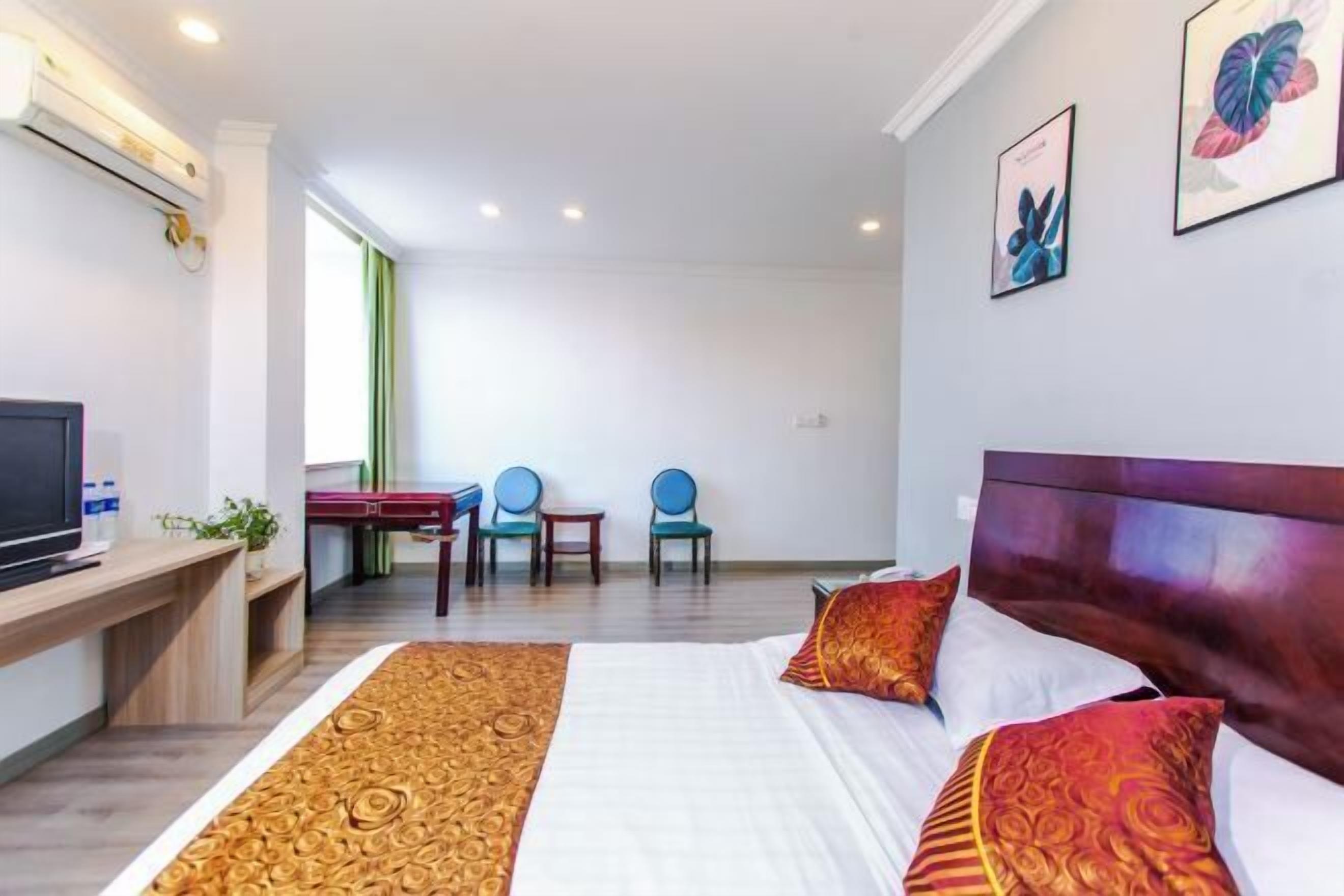 A hotel room with a bed, a desk, a television, and a window.