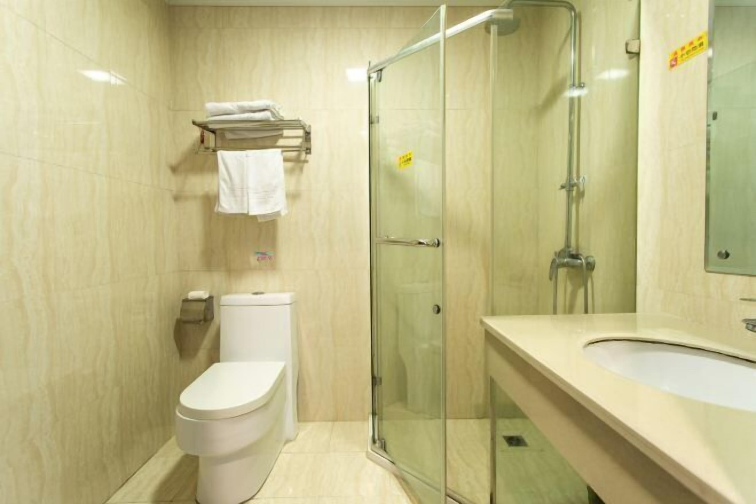 Un baño moderno con inodoro, ducha envuelta en vidrio y lavamanos.