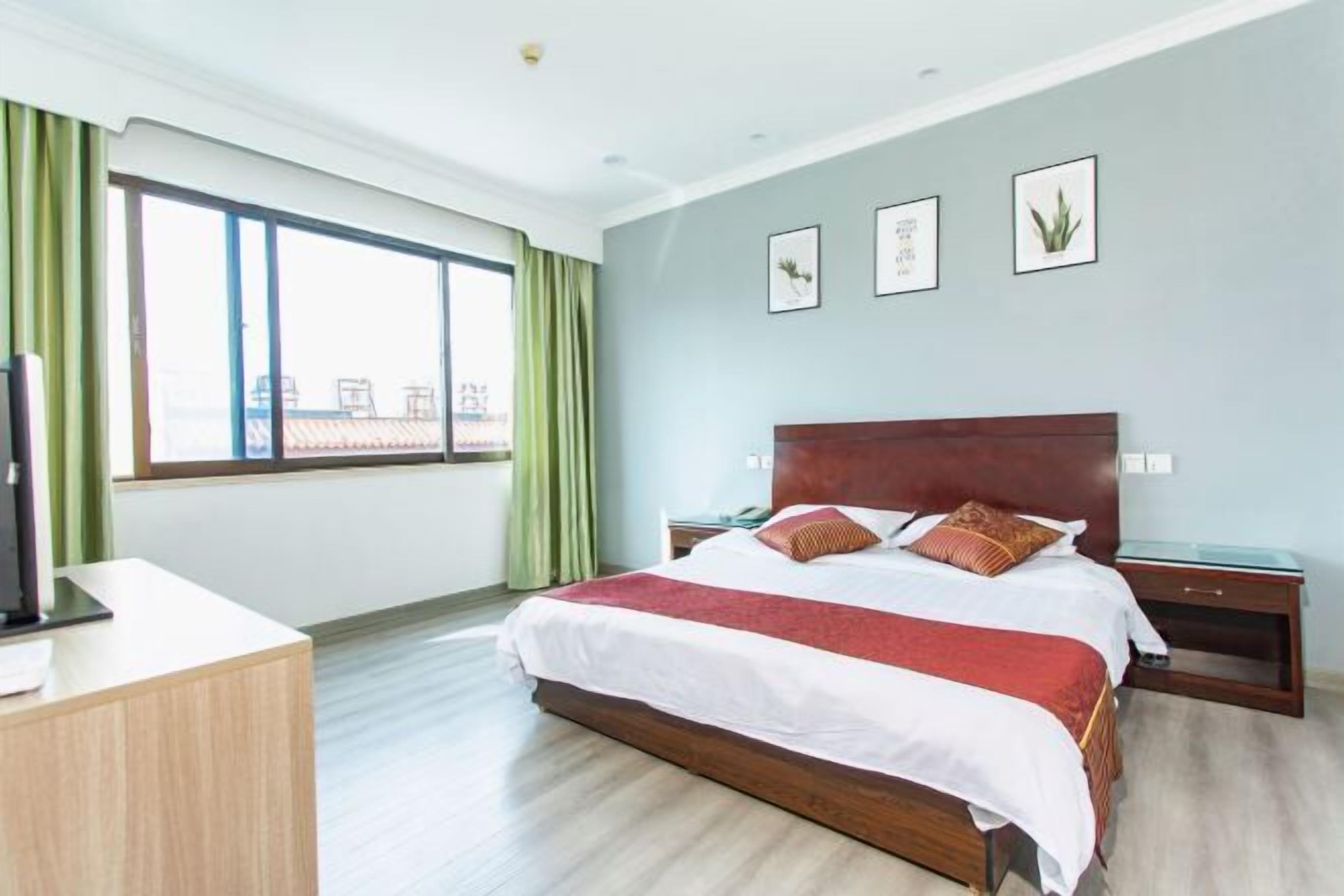 Ein modernes Hotelzimmer mit einem großen Bett, einem Schreibtisch und einem Fenster mit Vorhängen.