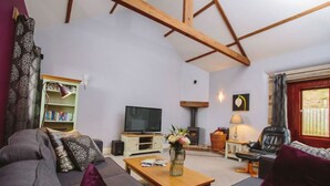 A living room with a sofa, a coffee table, a television, a bookshelf, and a fireplace. - Tower Barn (Brampton)