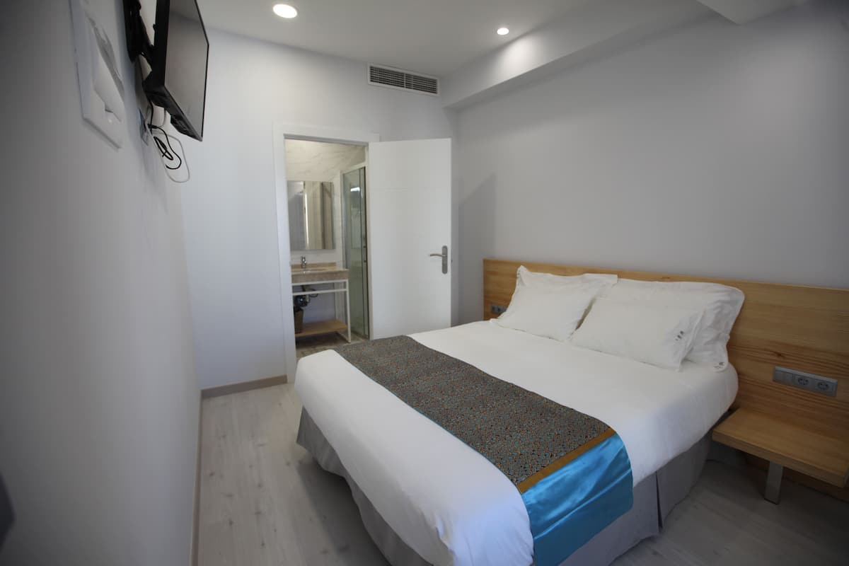 A modern hotel room with a large bed, a wooden headboard, and a walk-in closet.