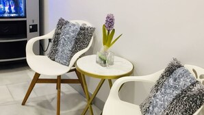 Two white chairs with wooden legs and patterned cushions, a small round table, and a vending machine. - Hostal Palacio Luna (Madrid)