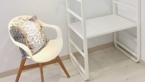 A white, open shelving unit with multiple compartments, a white chair with a patterned cushion, and a plain wall. - Hostal Palacio Luna (Madrid)