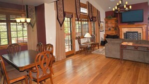 A spacious living room with a wooden dining table, chairs, a sofa, and a television. - Intermountain Chalet (Vail)