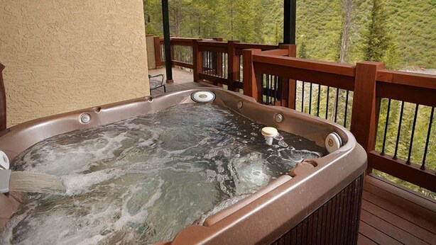 A hot tub on a wooden deck with a view of a forested area. - Intermountain Chalet (Vail)
