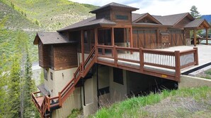 A wooden cabin with a balcony, set against a mountainous backdrop. - Intermountain Chalet (Vail)