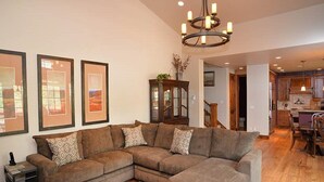 A living room with a sectional sofa, a rug, and framed artwork on the wall. - Intermountain Chalet (Vail)