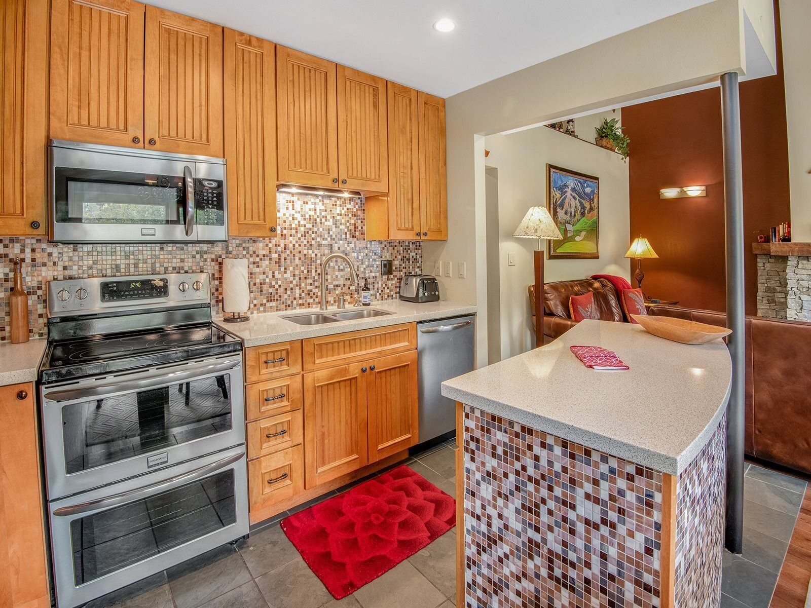 A modern kitchen with wooden cabinets, stainless steel appliances, and a tiled backsplash.