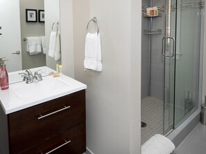 A modern bathroom with a white sink, dark wooden vanity, and a glass shower enclosure. - Vail 21 Condo 301 (Vail)