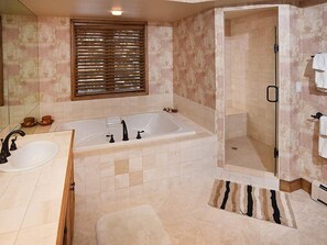 A bathroom with a large bathtub, a shower, and a sink.