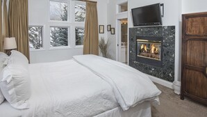 A bedroom with a bed, a fireplace, a television, and a wardrobe. - Vermont Road Chalet (Vail)