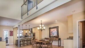 A spacious kitchen with a dining area, wooden flooring, and a high ceiling. - Vermont Road Chalet (Vail)