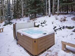 Un jacuzzi en un entorno nevado de bosque.