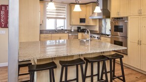 A modern kitchen with granite countertops, stainless steel appliances, and wooden cabinets. - Vermont Road Chalet (Vail)