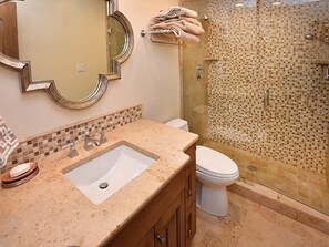 Une salle de bain avec un lavabo, un miroir et des toilettes.