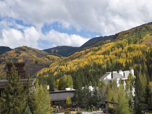 Un chalet avec une vue imprenable sur les montagnes, doté d’un imposant beffroi en bois et d’un bâtiment blanc au toit en pente.
